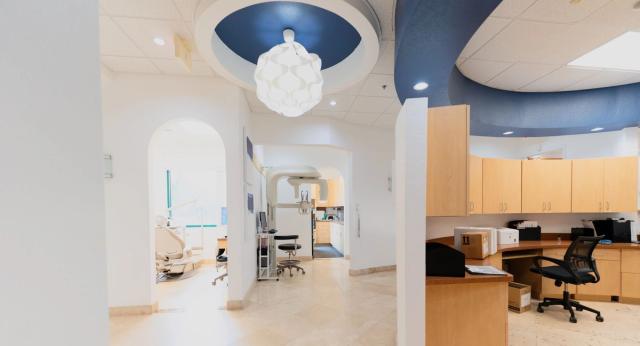 a dental office with a blue ceiling and a white chandelier hanging from the ceiling .