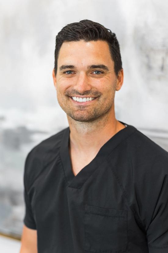 a man in a black scrub is smiling for the camera .