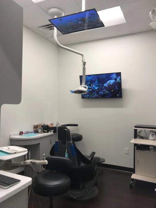 a dental office with a chair and a tv on the wall