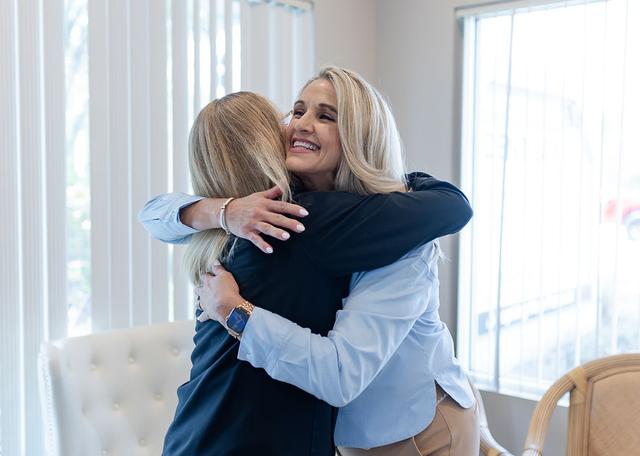 Two women hugging, one smiling happily.