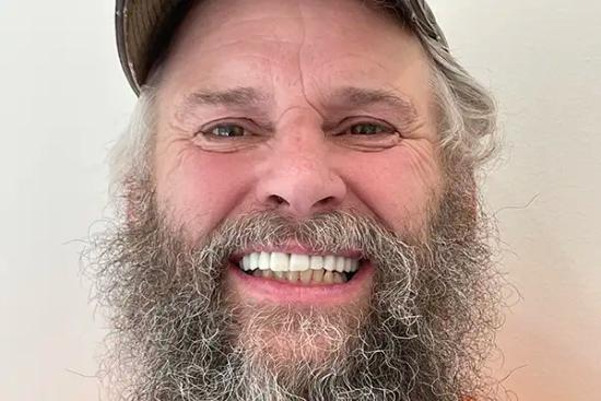 a man with a beard and mustache is smiling for the camera .