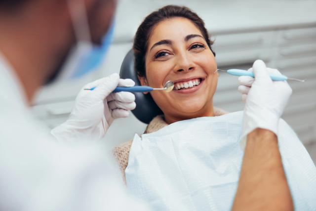 a woman is sitting in a dental chair while a dentist examines her teeth .