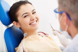 a woman is sitting in a dental chair while a dentist examines her teeth .