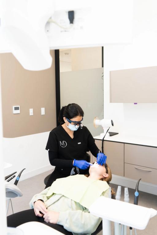 a woman is pointing at her teeth and smiling .