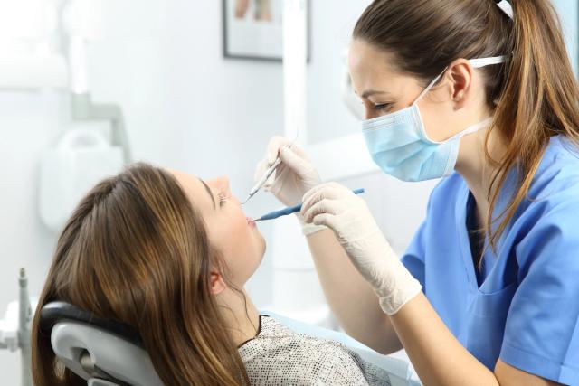 a woman is sitting in a dental chair while a dentist examines her teeth .