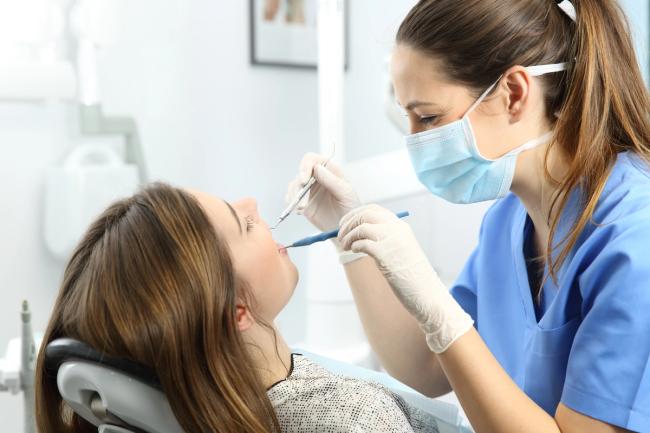 a woman is sitting in a dental chair while a dentist examines her teeth .