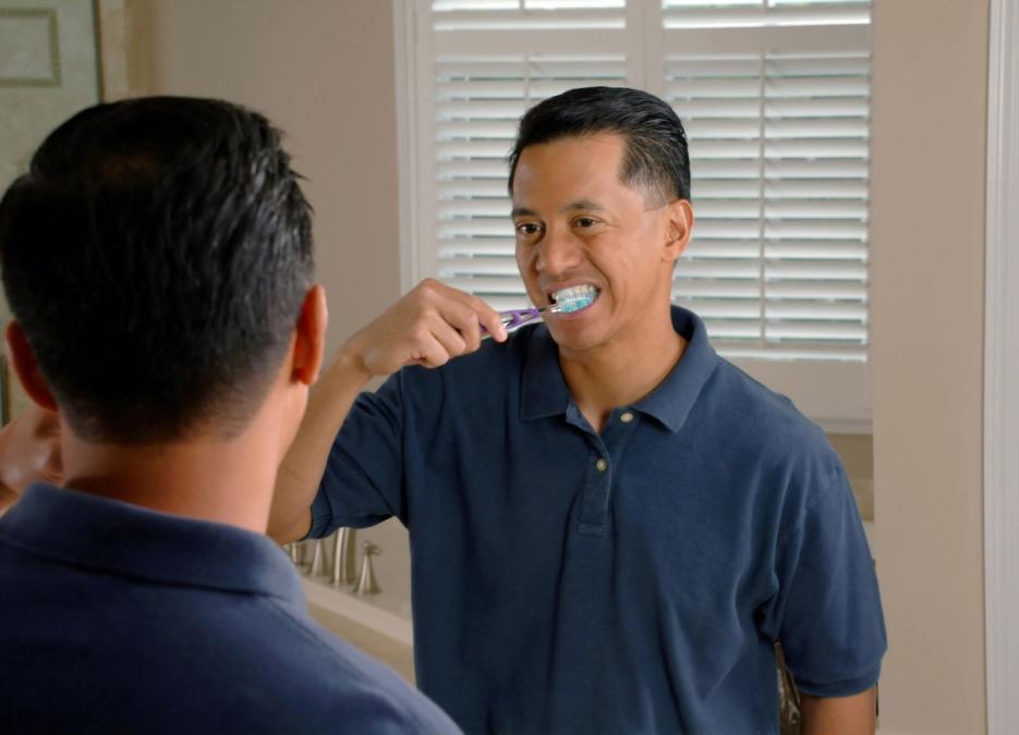 a man is brushing his teeth in front of a mirror in a bathroom .