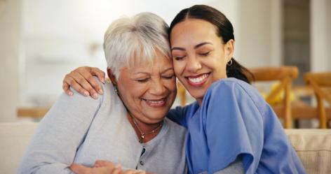 a nurse is hugging an older woman on a couch .