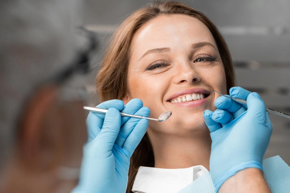 a woman is smiling while having her teeth examined by a dentist.