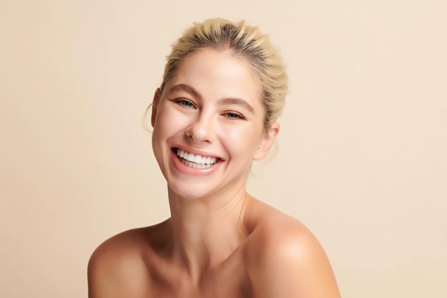 a woman with white teeth is smiling for the camera .