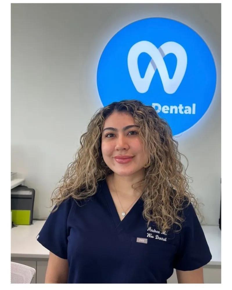 a woman in a scrub top is standing in front of a sign that says dental .