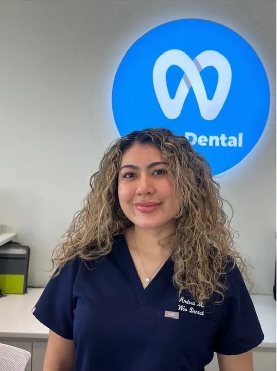 a woman in a scrub top is standing in front of a sign that says dental .