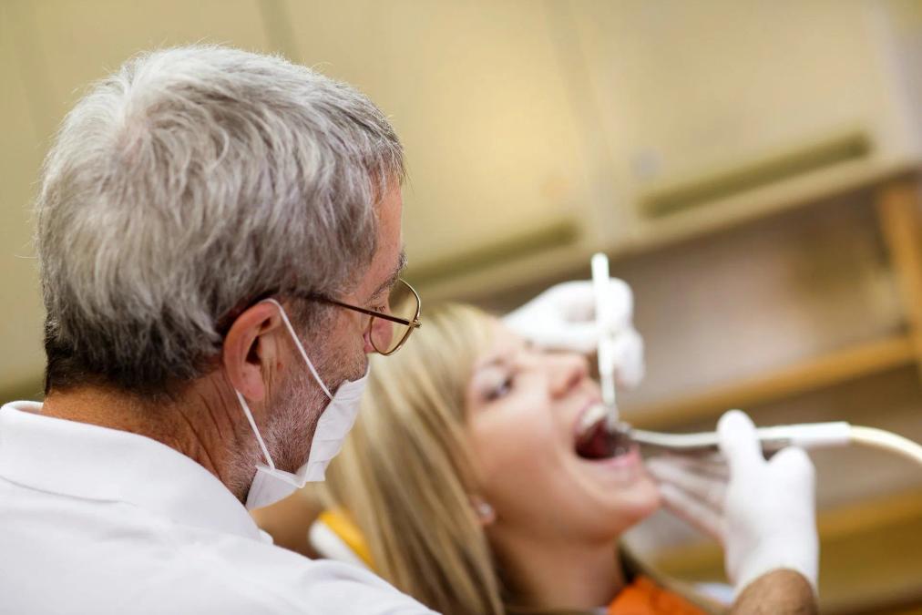 a dentist is examining a woman 's teeth in a dental office .