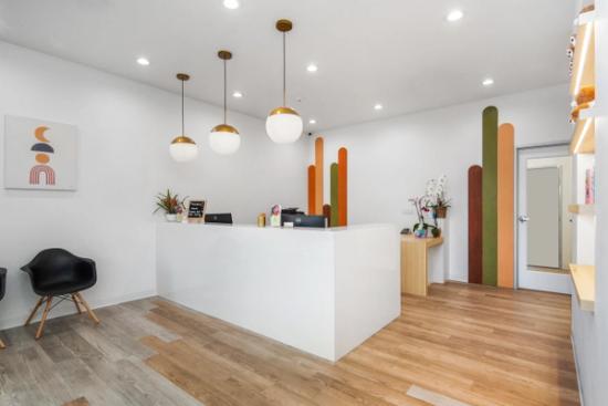 a reception area in a dental office with a white counter and wooden floors .