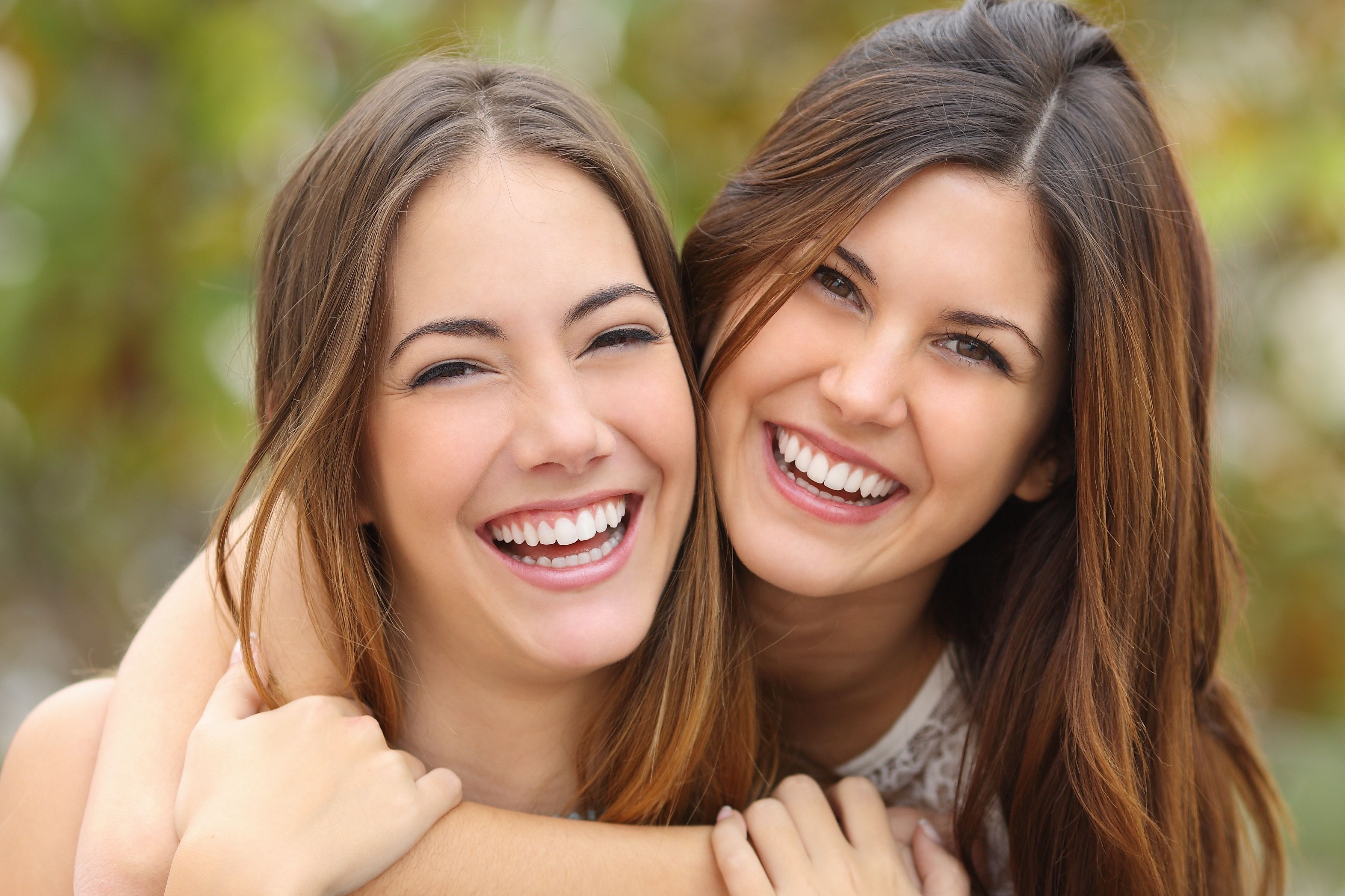 two young women are hugging each other and smiling .