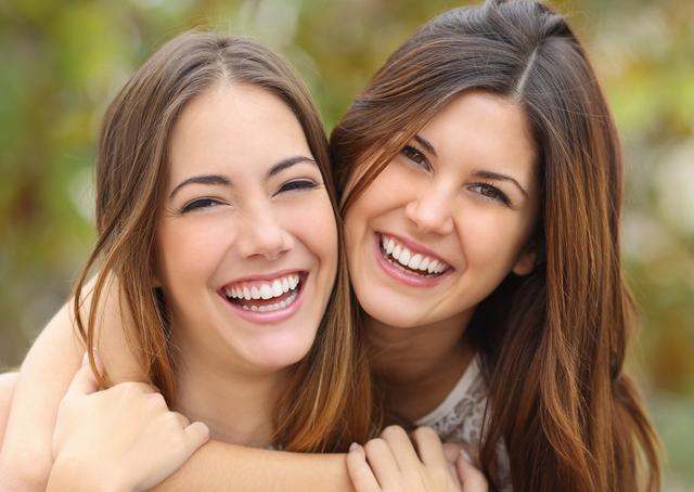 two young women are hugging each other and smiling .