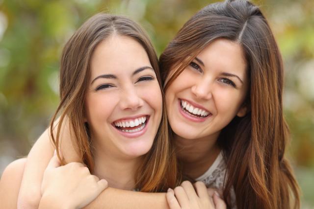 two young women are hugging each other and smiling .