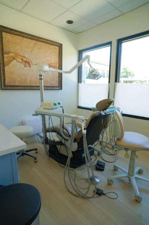 a dental office with a painting on the wall above the chair