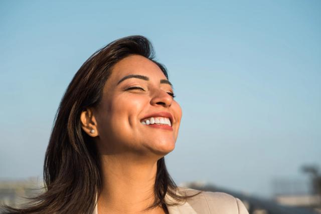 a woman is smiling with her eyes closed and her mouth open .