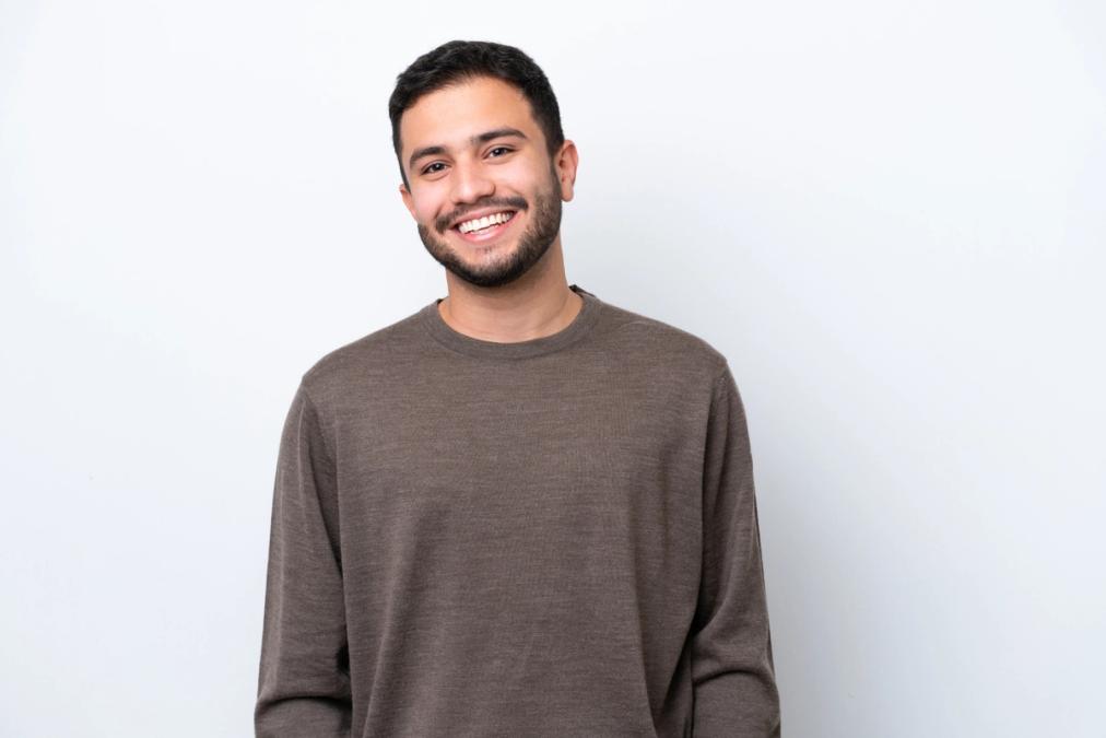 a young man with a beard is smiling and looking at the camera .