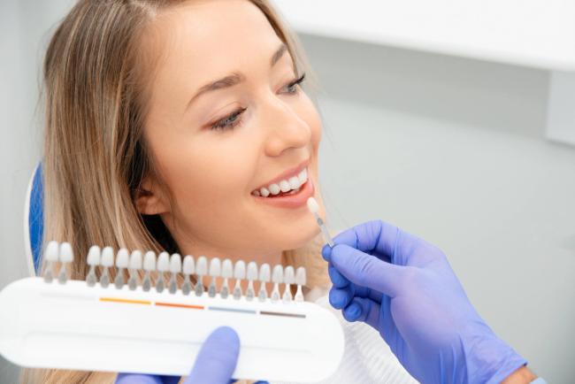 a woman is sitting in a dental chair while a dentist examines her teeth .
