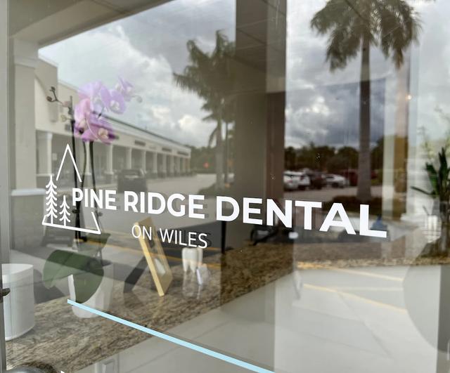 the logo for pine ridge dental on wiles is on the glass door of a dental office .