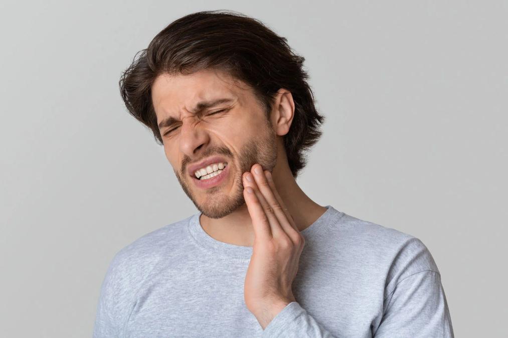 a man is holding his face in pain because of a toothache .