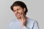 a man is holding his face in pain because of a toothache .