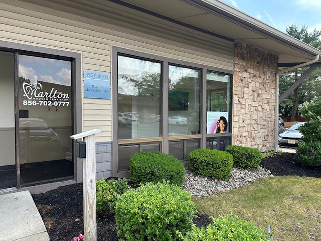 Exterior view of Marlton Modern Dentistry office with its entrance, windows, and business signage.