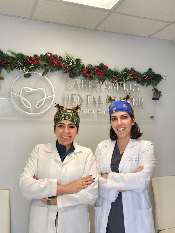 two female doctors pose in front of a sign for largo smiles dental center