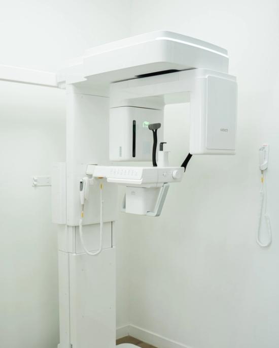 A white Vatech dental panoramic X-ray machine in a clean white room.