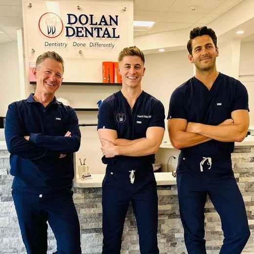 three men are posing in front of a sign that says dolan dental