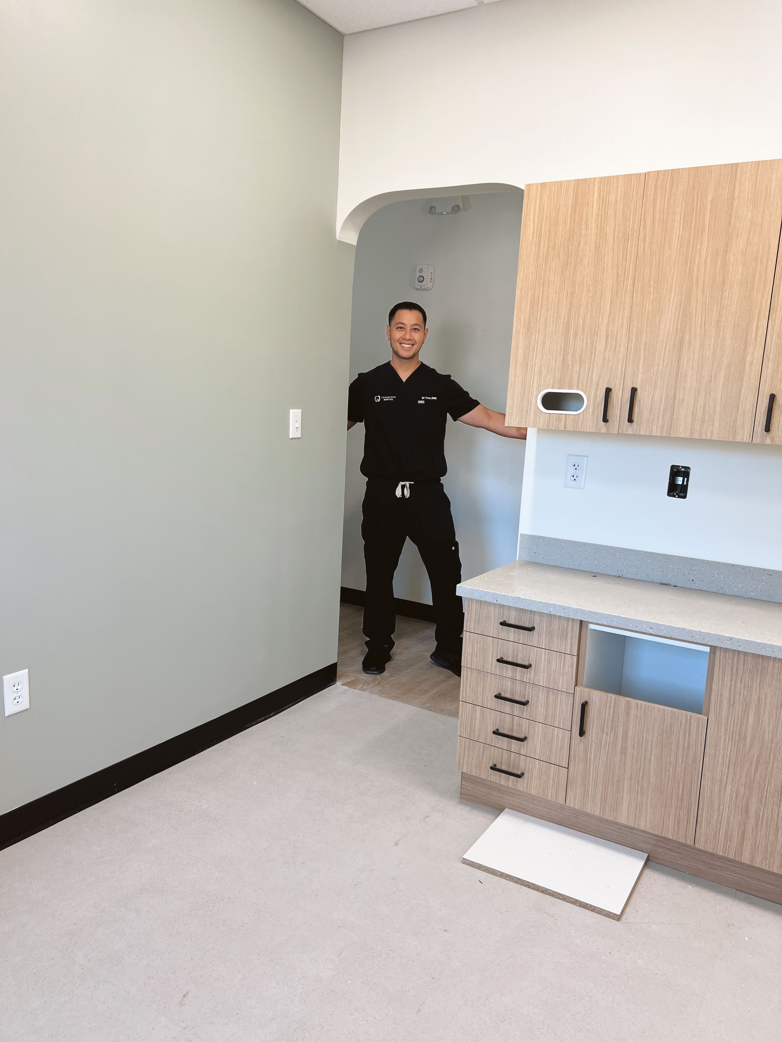 a man in a black scrub top stands in an empty room