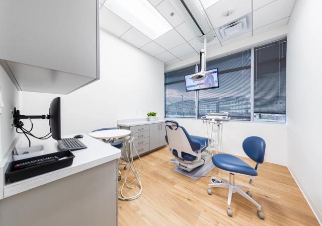 a dental office with a dental chair , desk , computer and television .