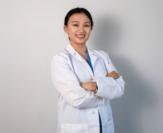 a woman in a white lab coat with her arms crossed