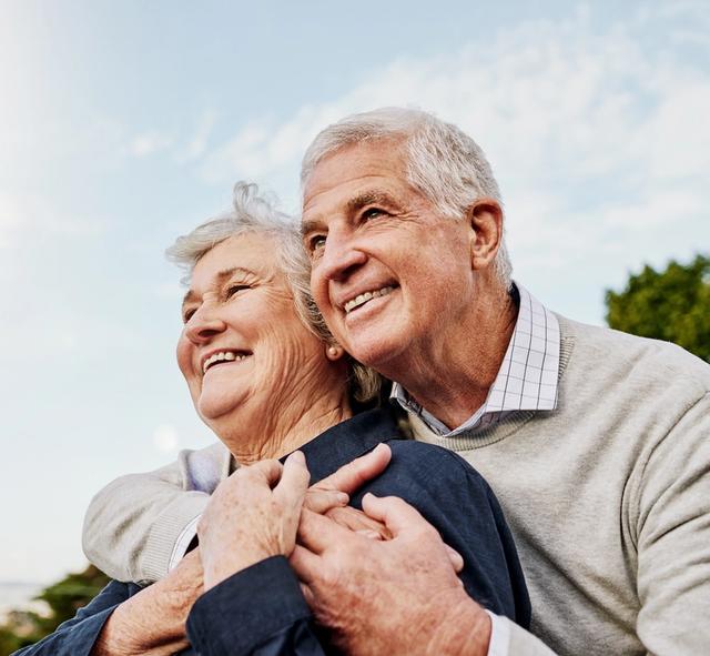an elderly couple is hugging each other and smiling .