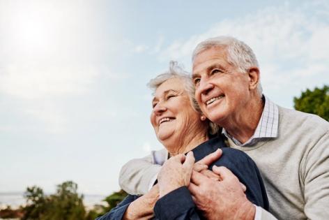 an elderly couple is hugging each other and smiling .