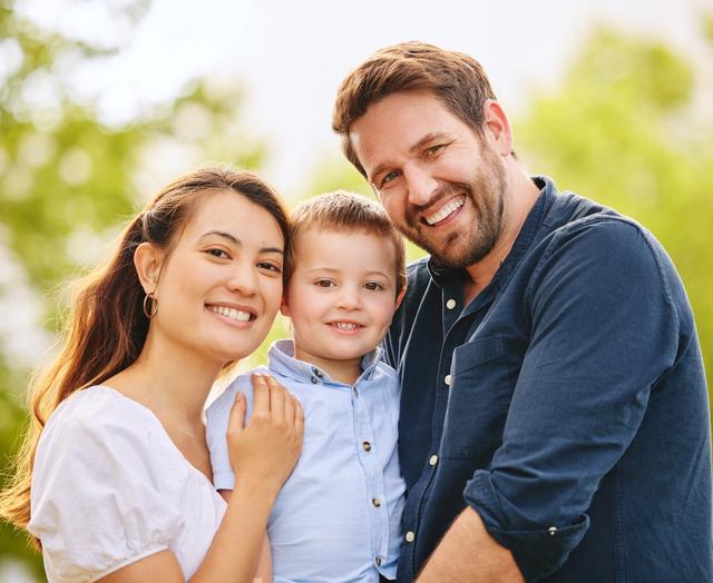 a family is posing for a picture together and smiling for the camera .
