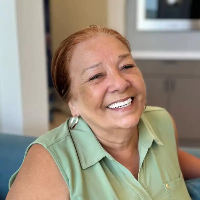 a woman in a green shirt is smiling while sitting on a couch .