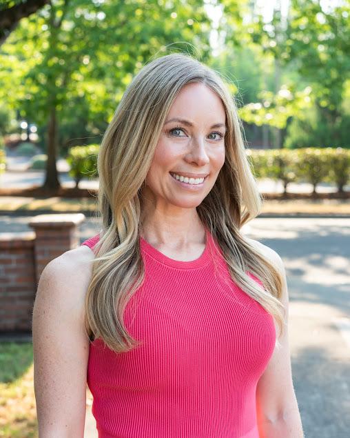 a woman in a pink tank top is smiling for the camera .