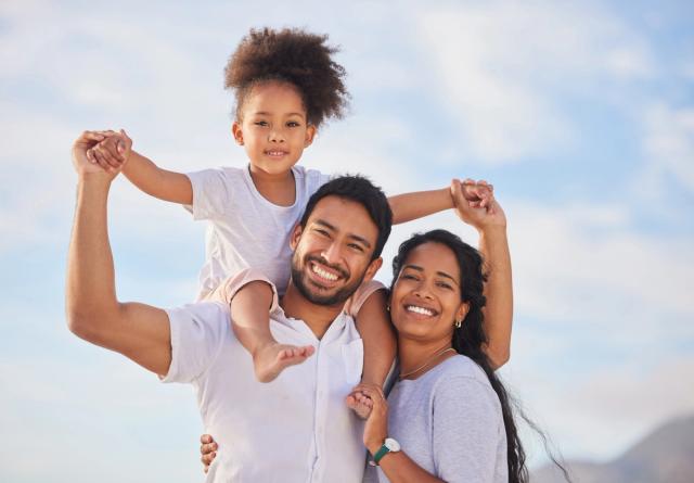 a man and woman are holding a little girl on their shoulders .