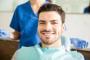 Man smiling in a dental chair with a dental professional behind him.