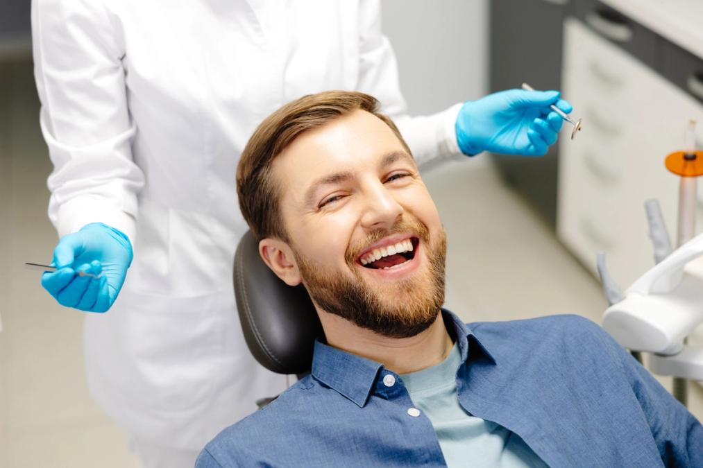 a man is smiling while sitting in a dental chair.