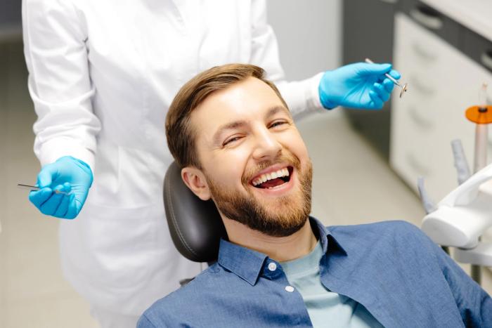 a man is smiling while sitting in a dental chair .