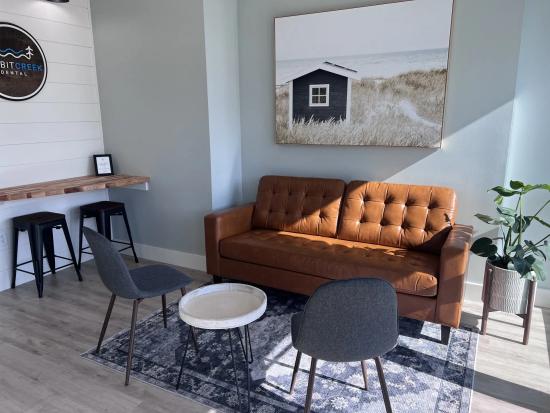 a living room with a brown couch , chairs , a table and a painting on the wall .