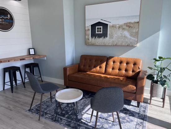 a living room with a brown couch , chairs , a table and a painting on the wall .