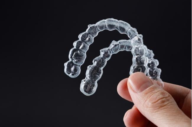 a person is holding a pair of clear braces in their hand .