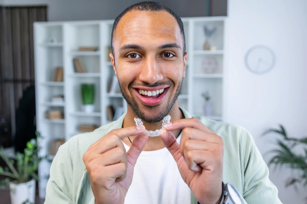 a man is holding a clear brace in his hands and smiling .
