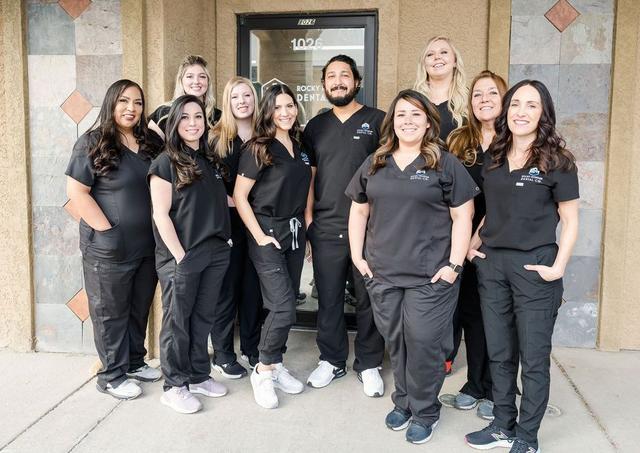 a group of people in scrubs are posing for a picture in front of a building .