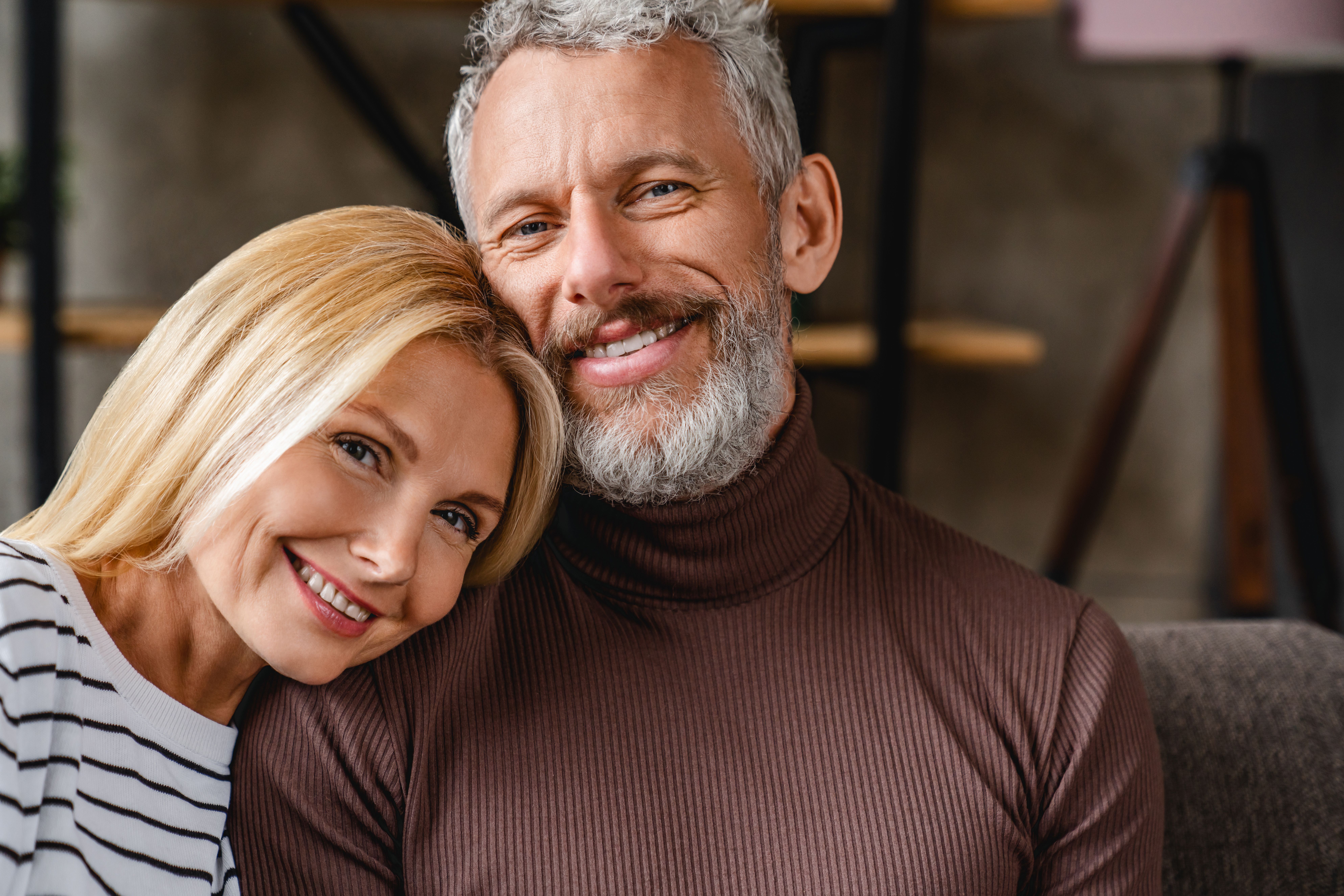 a man and a woman are smiling for the camera while sitting on a couch .